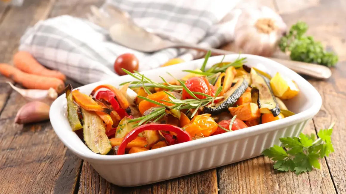 Deliciosas verduras al horno, como calabacín, pimientos y tomates cherry, con romero fresco, listas para servir.
