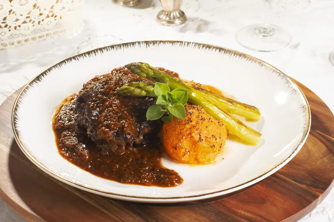 Carrilleras de ternera estofadas en salsa oscura, acompañadas de puré de boniato y espárragos trigueros.