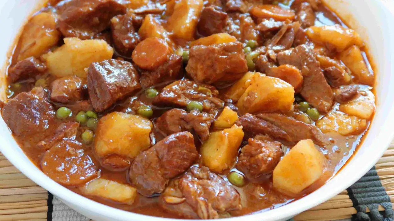 Guiso casero de magro con tomate, patatas y guisantes, listo para servir.