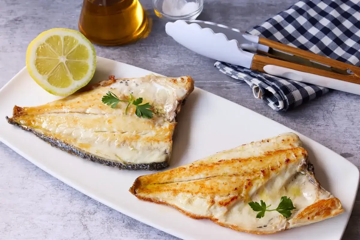 Dos filetes de dorada a la plancha, servidos con lim&oacute;n y perejil.