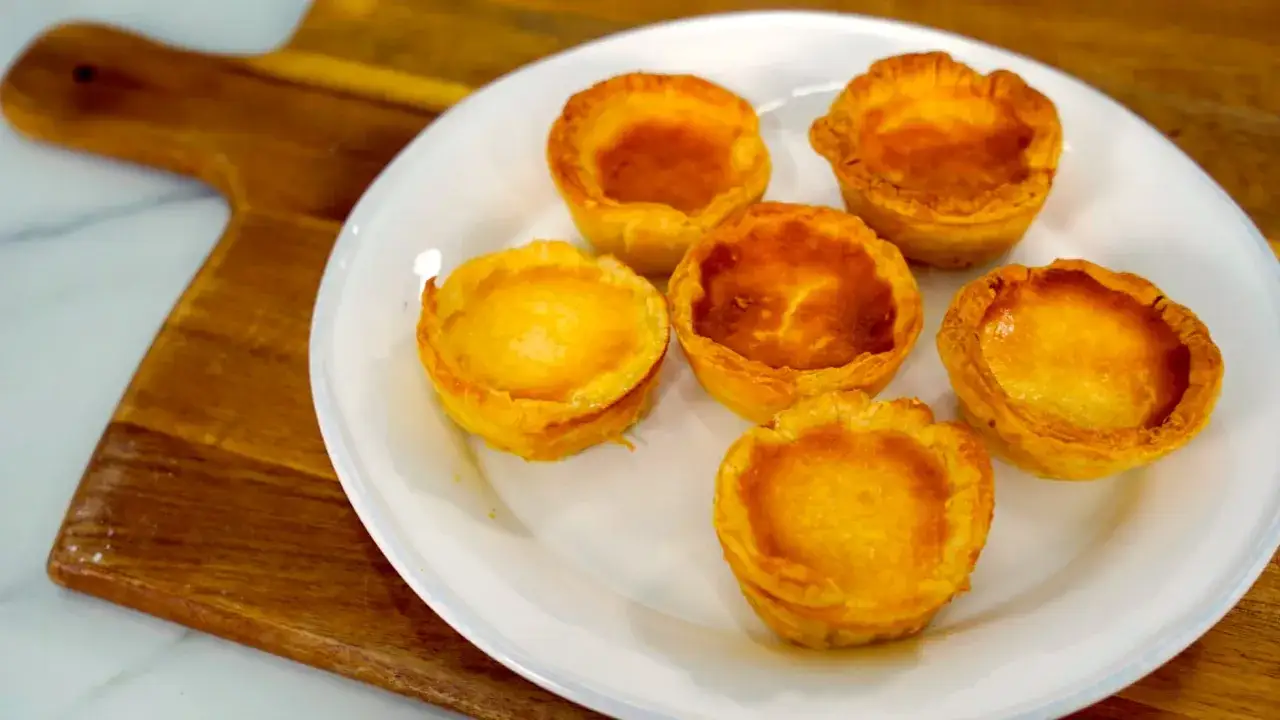 Seis pastelitos de arroz dorados y horneados en una placa blanca, listos para disfrutar.
