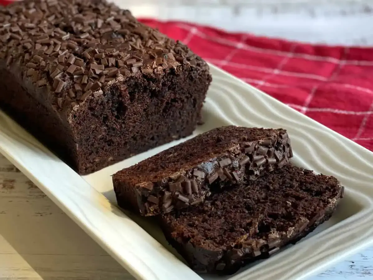 Delicioso bizcocho de pl&aacute;tano y chocolate, cubierto con virutas de chocolate, servido en una bandeja blanca.
