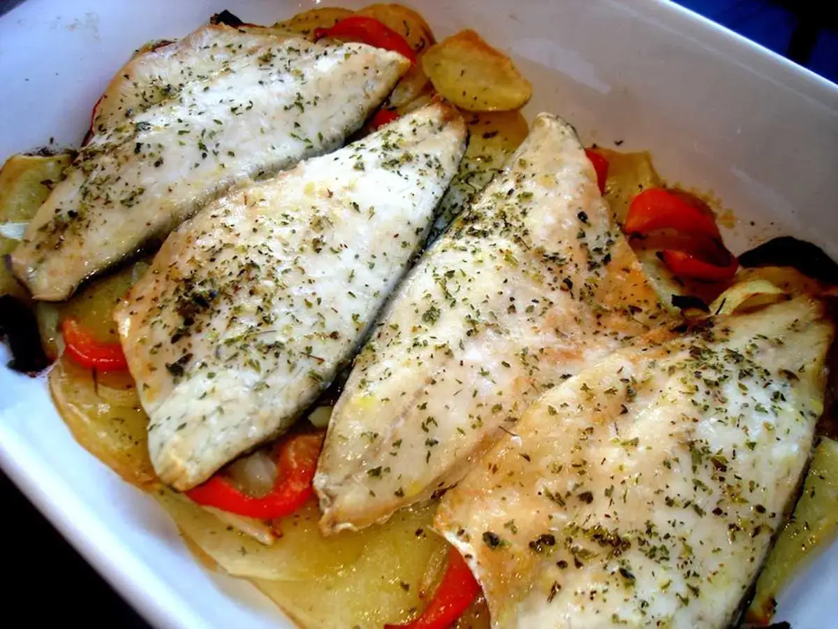 Filetes de lubina al horno, tiernos y jugosos, sobre una cama de patatas y pimientos rojos. &iexcl;Un plato delicioso!