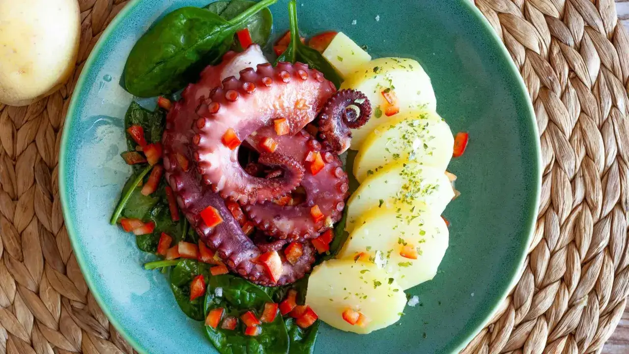 Delicioso pulpo a la plancha con patatas cocidas y espinacas frescas. Un plato lleno de sabor y color.