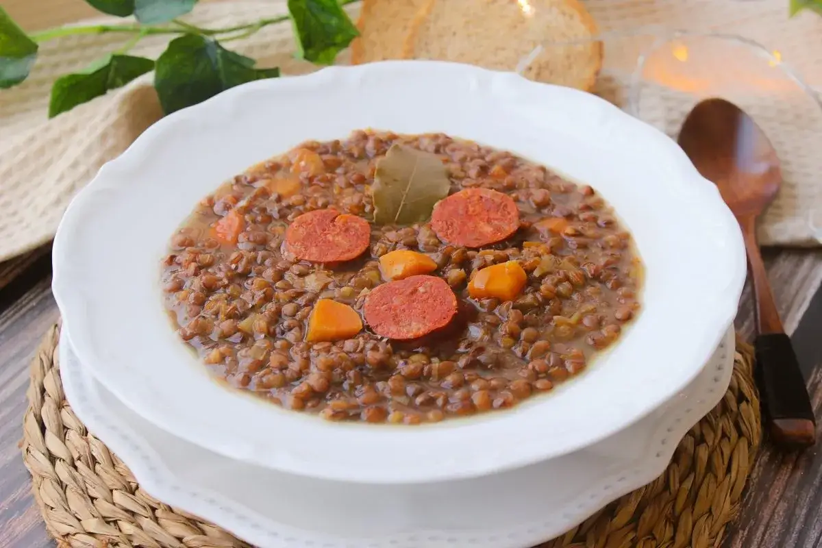 Un plato humeante de lentejas de bote con chorizo y zanahoria, decorado con hojas de laurel. Perfecto para un día frío.