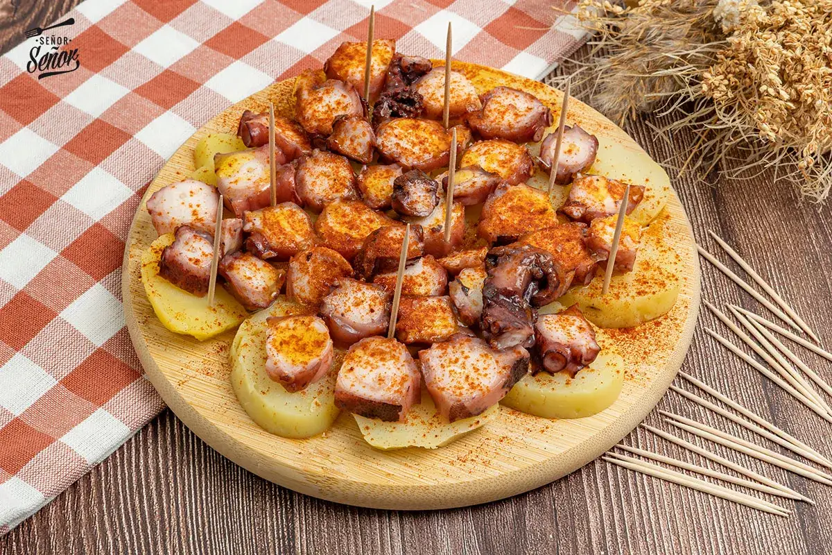 Pulpo a la gallega servido en rodajas de patata, espolvoreado con piment&oacute;n y servido con palillos.