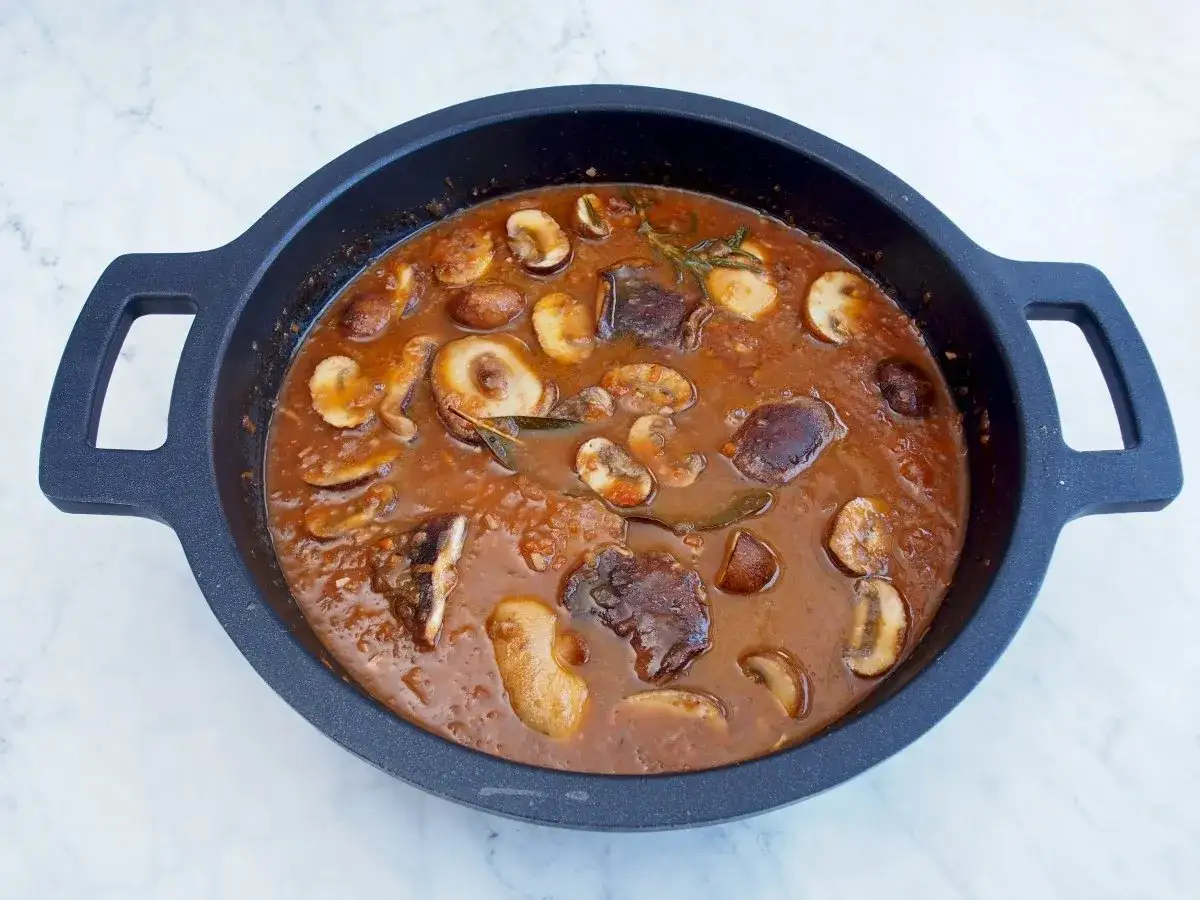 Fricando de ternera con champi&ntilde;ones y hierbas arom&aacute;ticas en una sart&eacute;n.