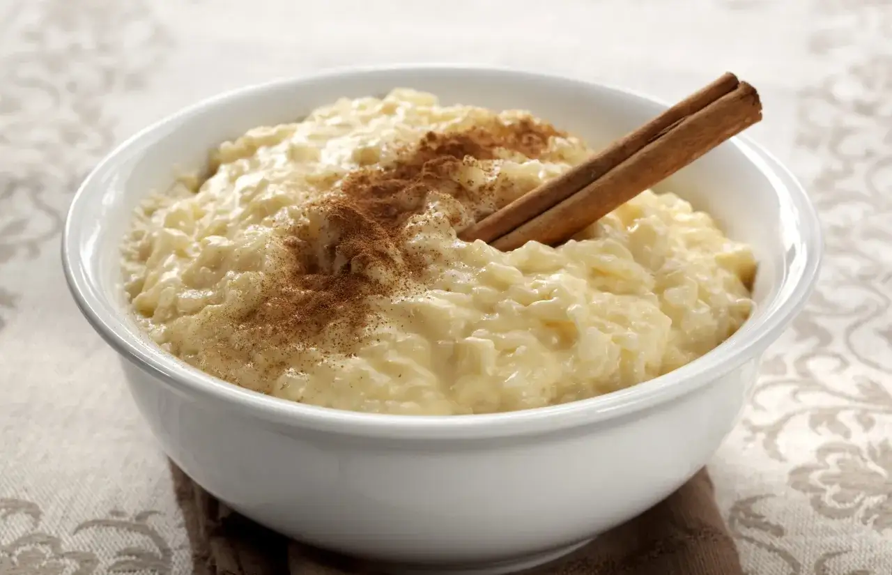 Delicioso arroz con leche cremoso, espolvoreado con canela y una rama de canela. Perfecto para aprender como hacer arroz con leche.