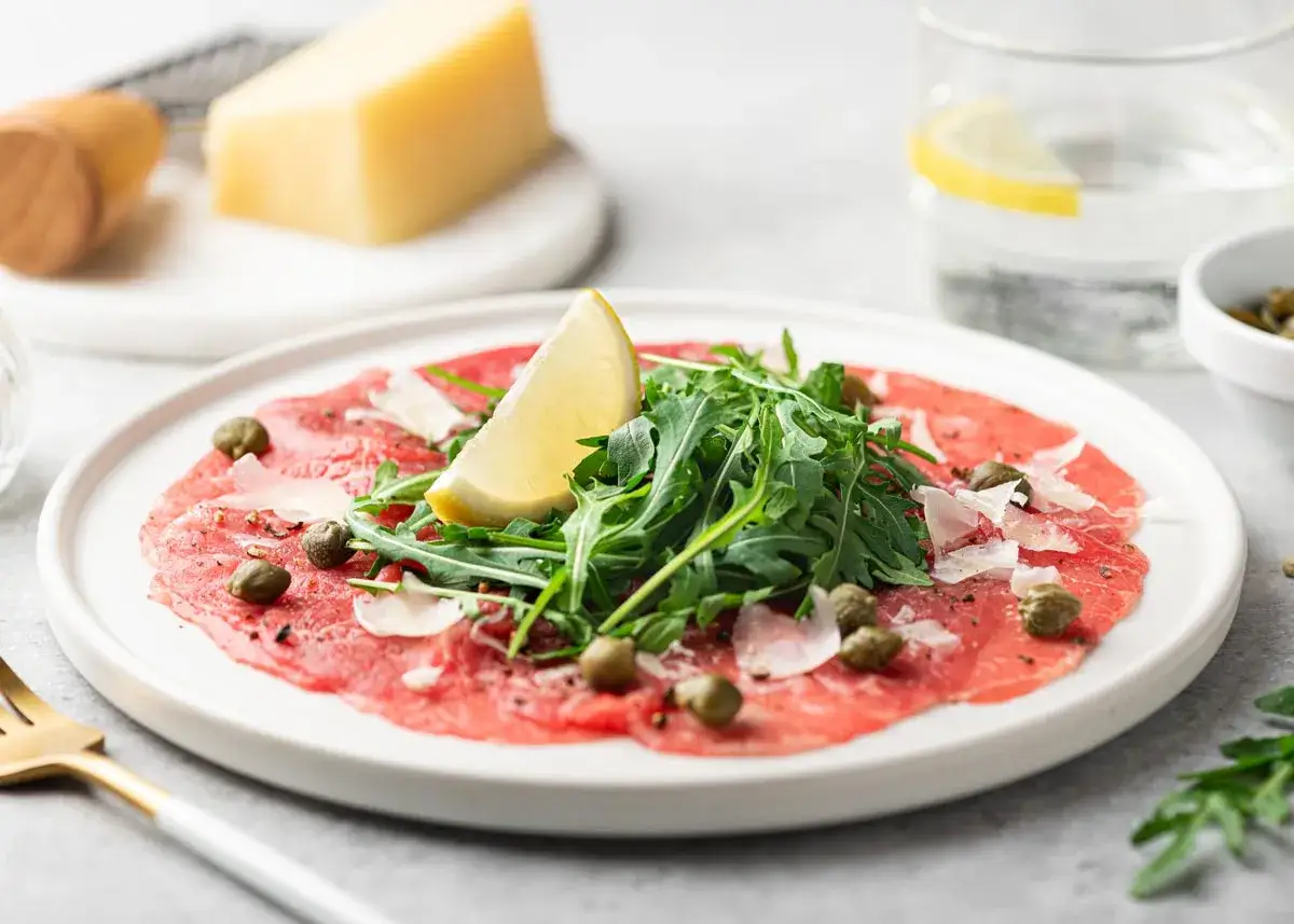 Delicioso carpaccio de ternera con r&uacute;cula fresca, alcaparras, lascas de parmesano y un toque de lim&oacute;n.