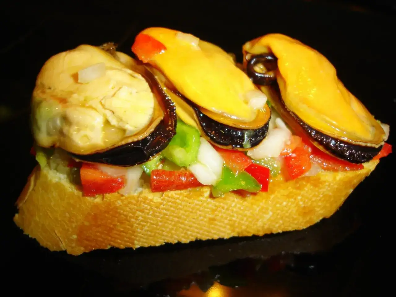Tosta con mejillones a la vinagreta, pimientos y cebolla picados. Un bocado fresco y sabroso.