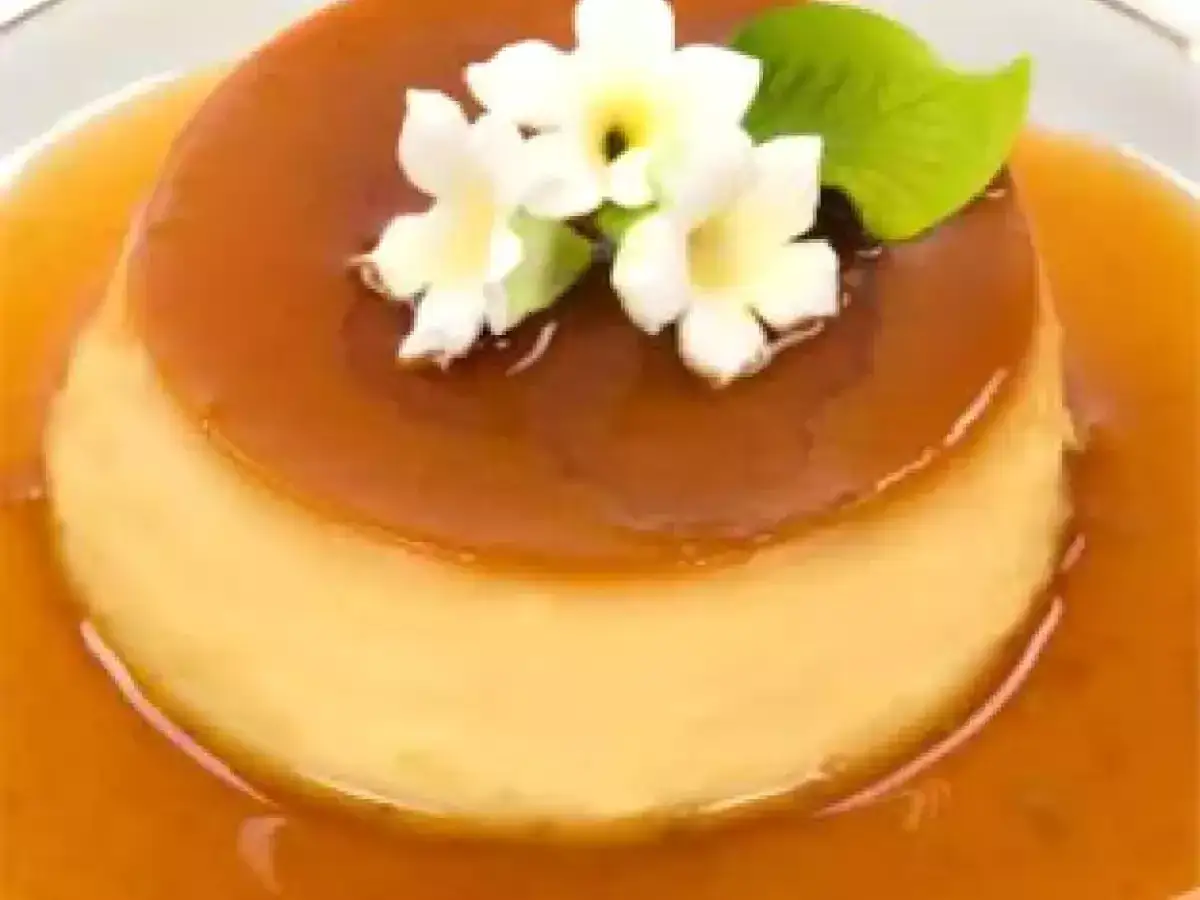Delicioso flan de yogur con caramelo l&iacute;quido, decorado con flores blancas y una hoja verde. &iexcl;Un postre irresistible!