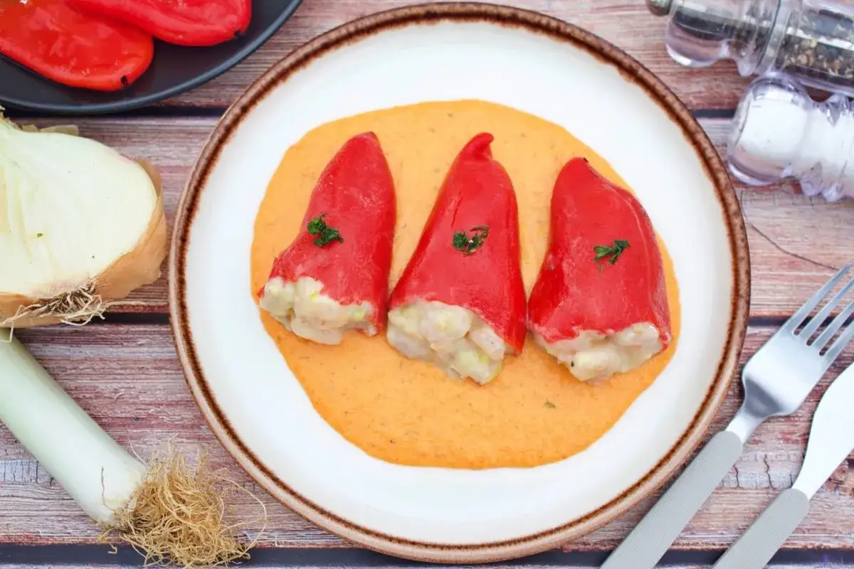 Pimientos del piquillo rellenos de gambas, servidos sobre una cremosa salsa.