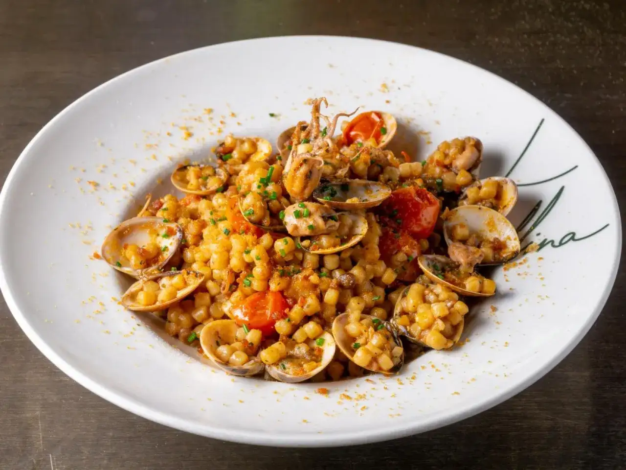 Un plato de pasta con almejas, trozos de calamar y tomates, espolvoreado con perejil picado. Un delicioso spaghetti frutti di mare.