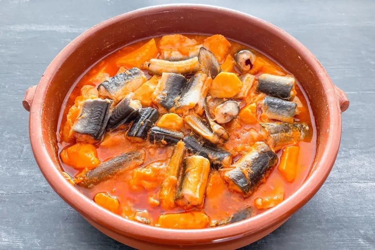 Un cuenco de barro con all i pebre, un guiso tradicional valenciano de anguilas y patatas en salsa roja.