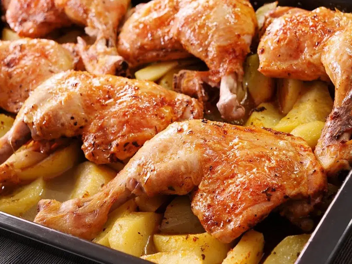 Rustidera de pollo dorada y jugosa con patatas asadas, lista para servir.