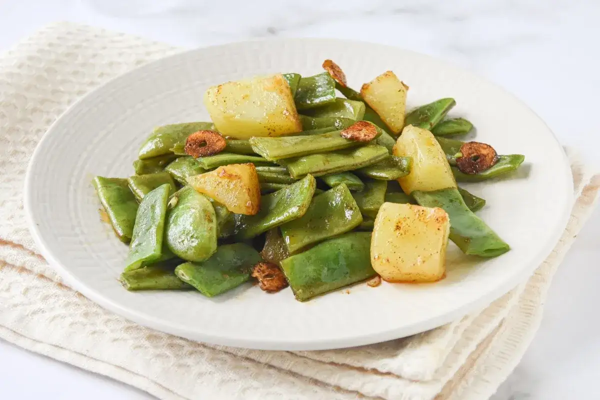 Plato de jud&iacute;as verdes con patatas y ajo crujiente. Un guiso sencillo y sabroso.