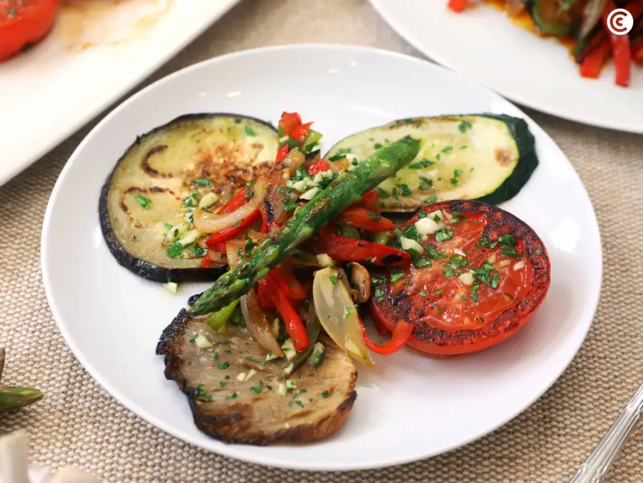 Plato de verduras al horno: berenjena, calabacín, tomate, pimiento rojo, cebolla y espárragos, todo salteado con ajo y perejil.
