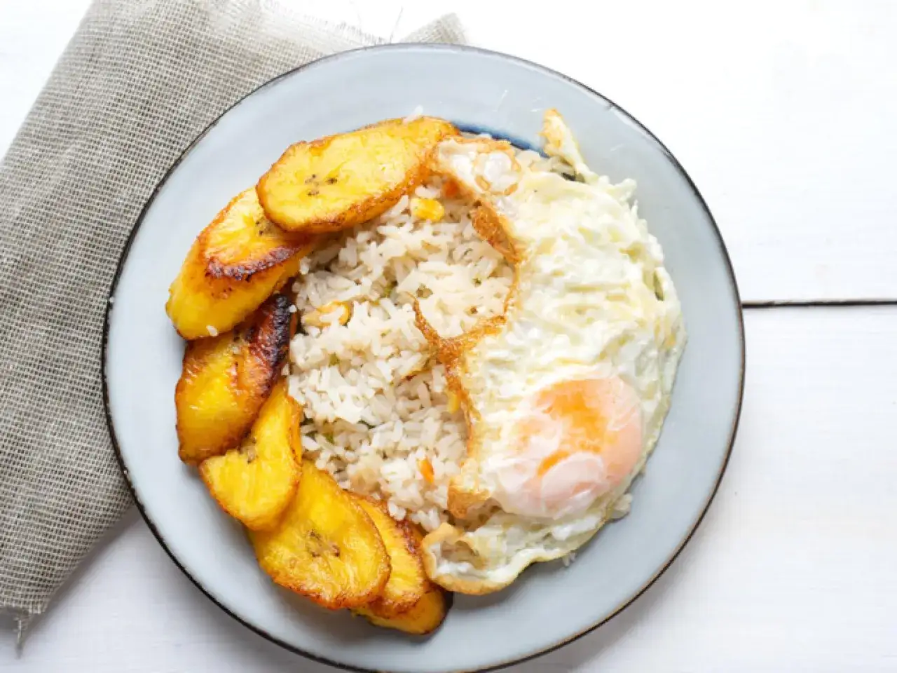 Plato de arroz a la cubana con huevo frito y pl&aacute;tanos maduros fritos.