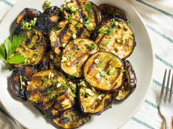 Rodajas de berenjenas a la plancha, doradas y tiernas, con ajo picado y perejil fresco. Un plato sencillo y delicioso.