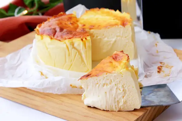 Tarta de queso en freidora de aire, dorada y cremosa, con una porción lista para disfrutar.