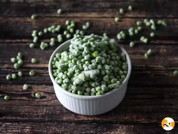 Un cuenco blanco lleno de guisantes congelados, perfecto para tus próximas recetas con guisantes congelados.