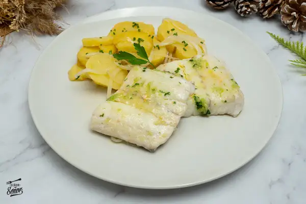 Dos filetes de merluza jugosos con patatas y cebolla, decorado con perejil fresco. Un plato delicioso y saludable.