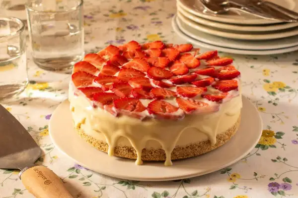 Tarta de frutas frescas cubierta de fresas y glaseado blanco cremoso.