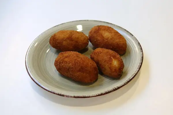 Cuatro croquetas de pollo de la abuela doradas y crujientes en un plato.