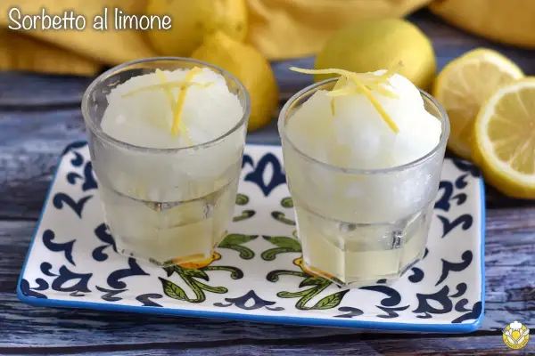 Dos vasos de refrescante helado de limón, adornados con ralladura de limón, sobre una bandeja decorada.