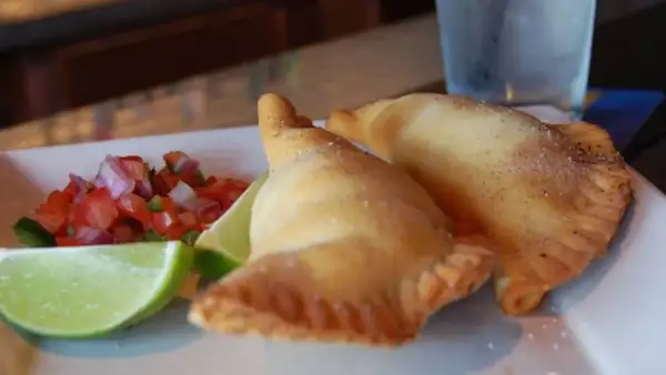 Dos empanadillas doradas con pico de gallo y limón. ¡Perfectos rellenos para empanadillas!