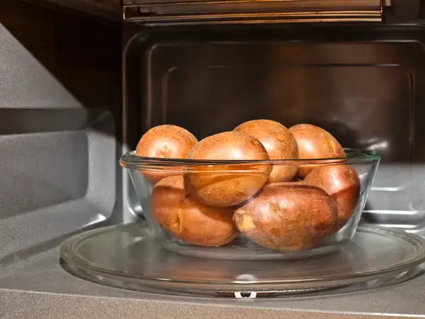 Patatas al microondas en un bol de cristal, listas para una cocción rápida y fácil.