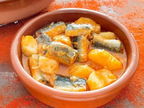 Un cuenco de barro con trozos de pescado y patatas en salsa, un delicioso all i pebre.