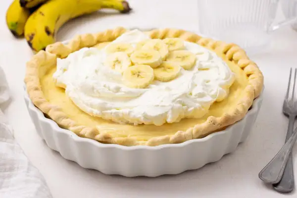 Delicioso pastel de plátano con crema batida y rodajas de plátano fresco. Un postre perfecto para cualquier ocasión.