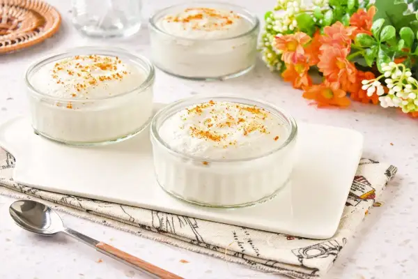 Tres ramequines de mousse de yogur con un toque de canela, servidos en una bandeja blanca.