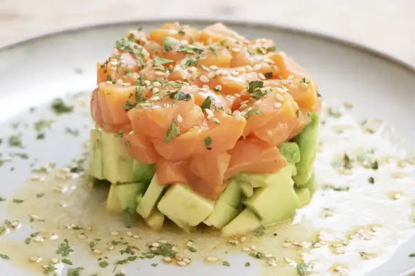 Delicioso tartar de salmón ahumado y aguacate, ideal para tus recetas con salmón ahumado. Adornado con sésamo y perejil.