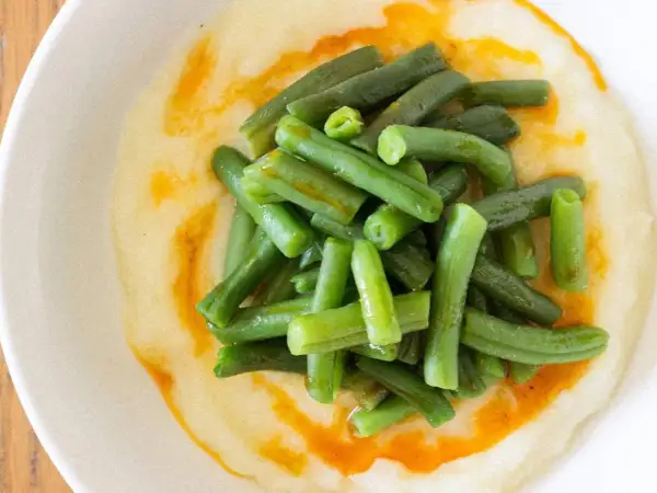 Judías verdes frescas y tiernas sobre un puré cremoso, con un toque de aceite de pimentón. Un plato sencillo y delicioso de judías verdes con patatas.