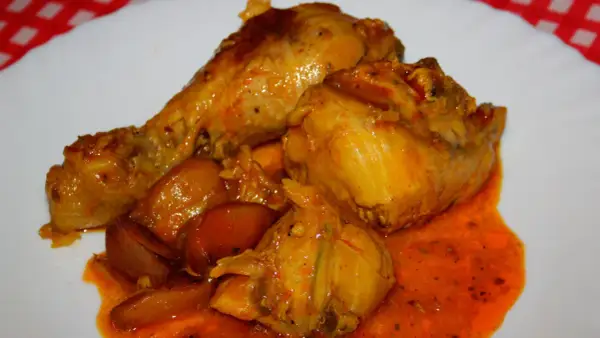 Sabroso pavo en salsa con cebollas, bañado en una rica y anaranjada salsa.