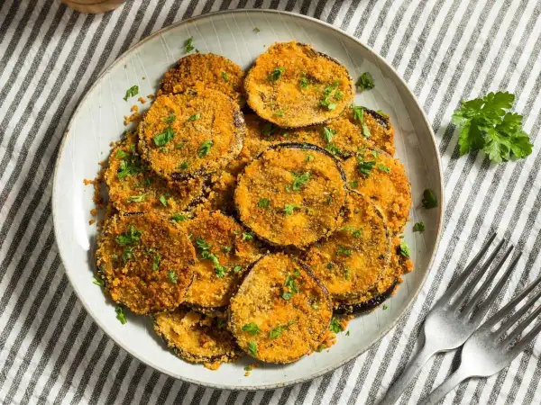 Berenjenas rebozadas con harina y huevo, doradas y crujientes, espolvoreadas con perejil fresco. Un plato delicioso y fácil de preparar.
