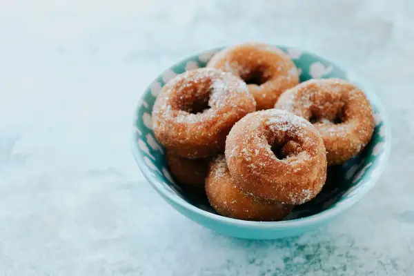 Rosquillas de Semana Santa espolvoreadas con azúcar, servidas en un cuenco azul.