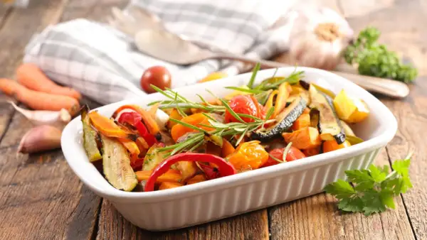 Deliciosas verduras al horno, como calabacín, pimientos y tomates cherry, con romero fresco, listas para servir.